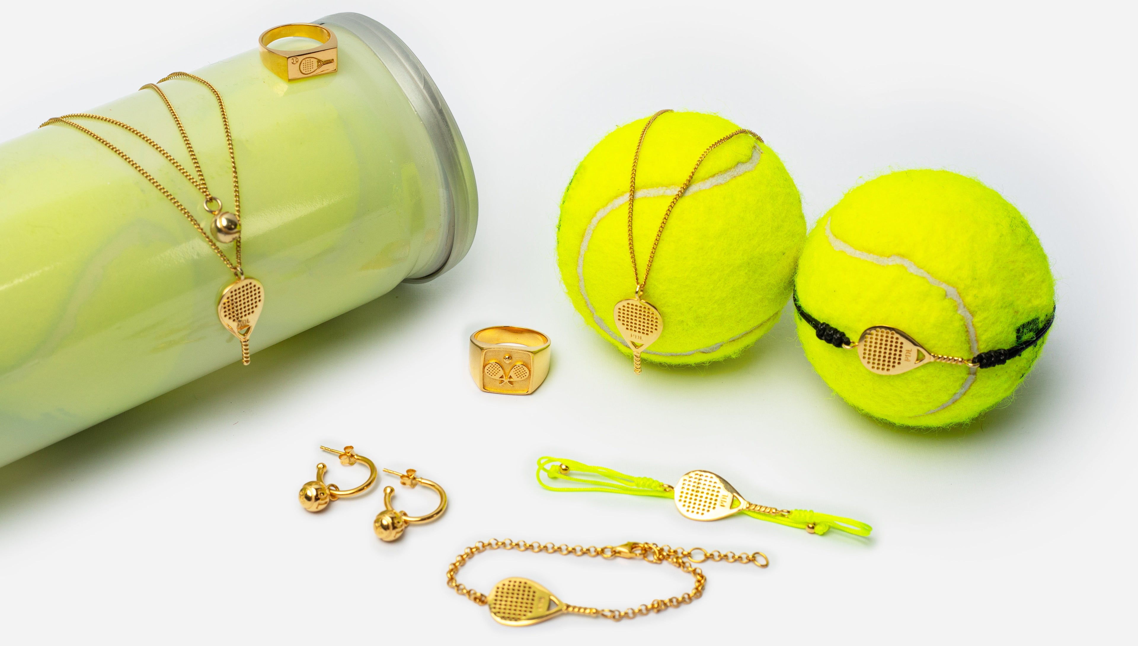 Gold jewelry with tennis ball designs on a white background